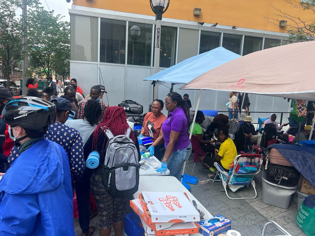 Community members gathered beside an outdoor information and supplies table