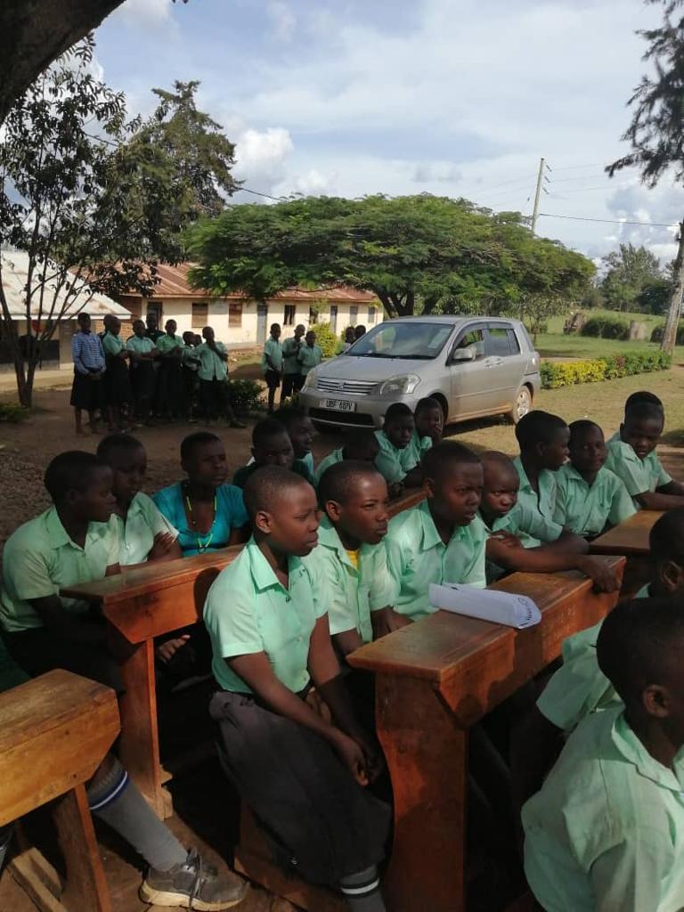 Students seated at desks outdoors during a school session